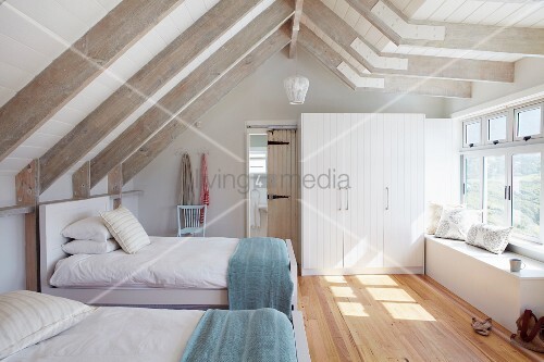 Gästezimmer mit zwei Einzelbetten in hellem Dachgeschoss mit weiß
