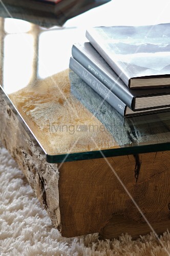 Bücherstapel auf bodennahem tisch mit glasplatte auf holzstamm ... Holzstämme als tisch