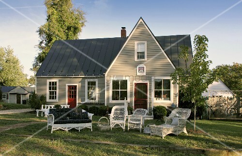 Graues Holzhaus mit Rattanmöbeln im Garten – Bild kaufen – living4media