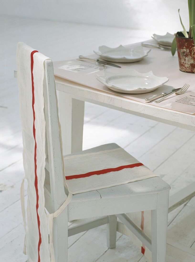 Ein gedeckter Esstisch mit Husse über Stuhl