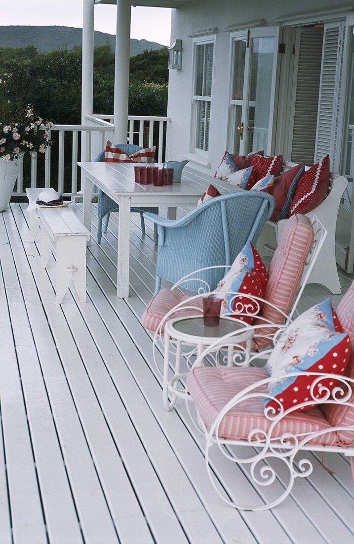 Gartenmöbel mit bunten Polster- und Sitzkissen auf einer Veranda