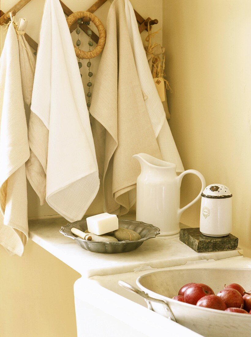 Handtücher am Holzhaken und Äpfel in der Spüle einer Küche