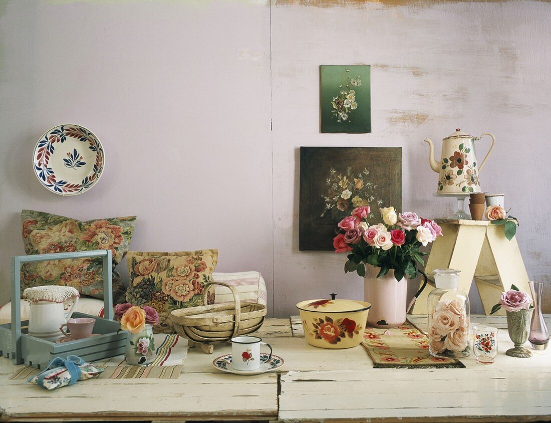 Diverses Geschirr mit Blumenmuster und Blumenvasen auf rustikalen Holztisch