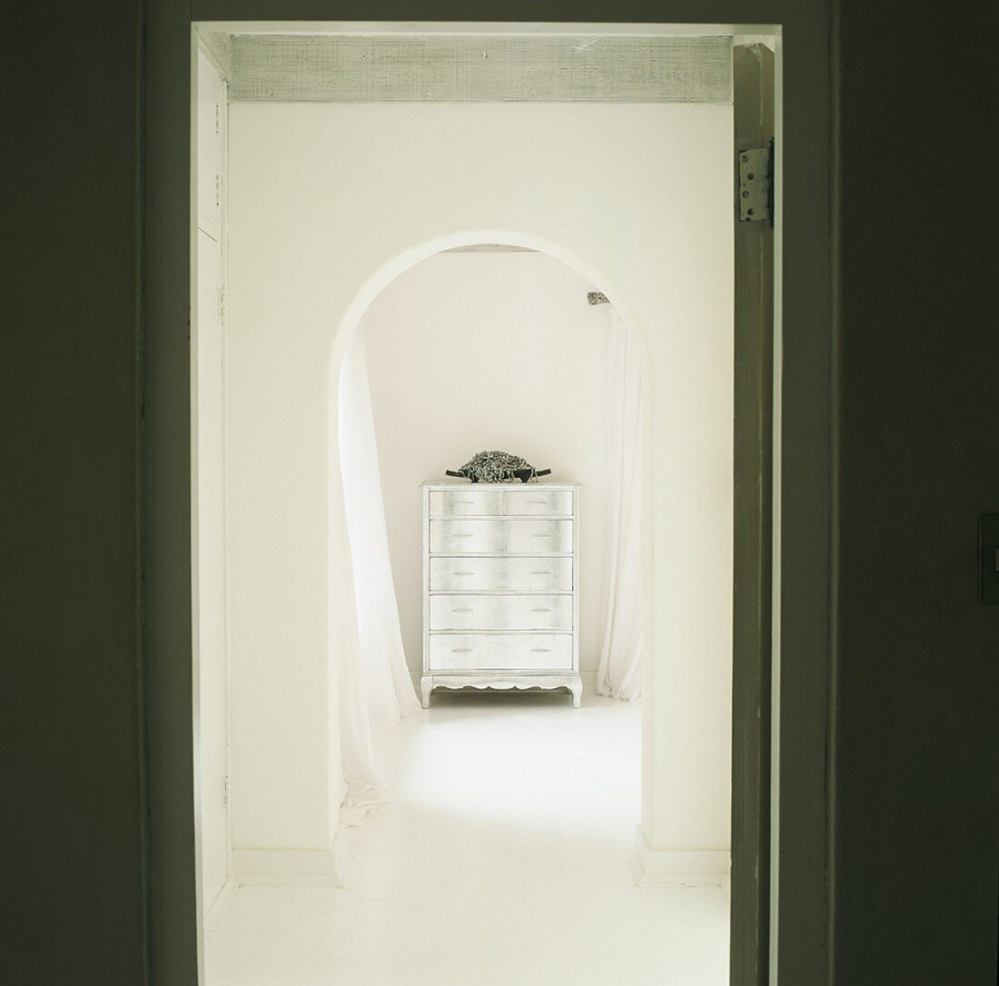 Blick durch offene Tür auf eine verspiegelte Wandkommode