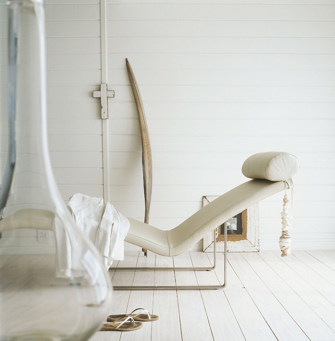 Ein Liegestuhl und Damenschuhe im weiß gestrichenen Holzhaus