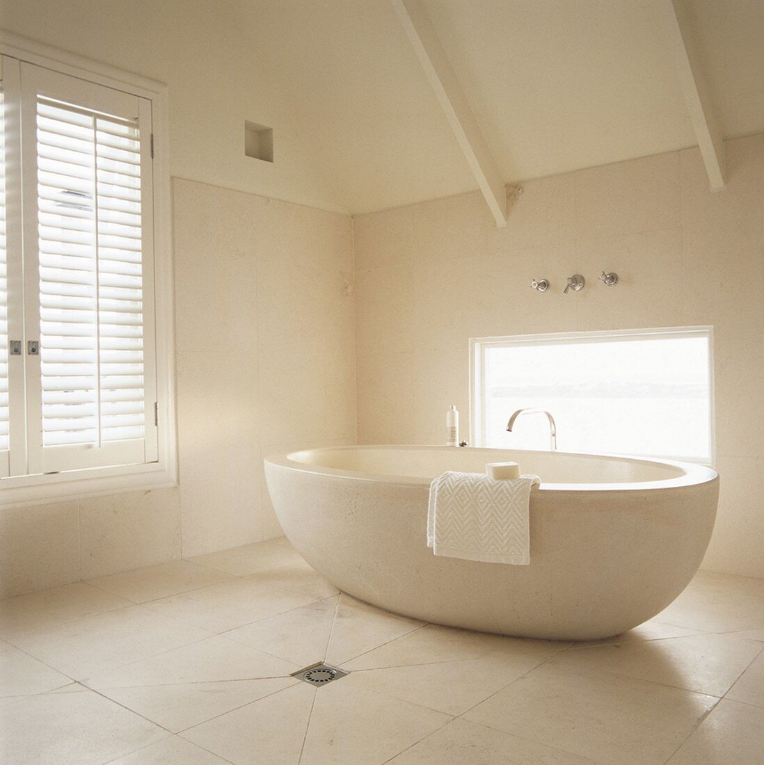 Eine frei stehende runde Badewanne aus Naturstein im renouvierten Dachstuhl