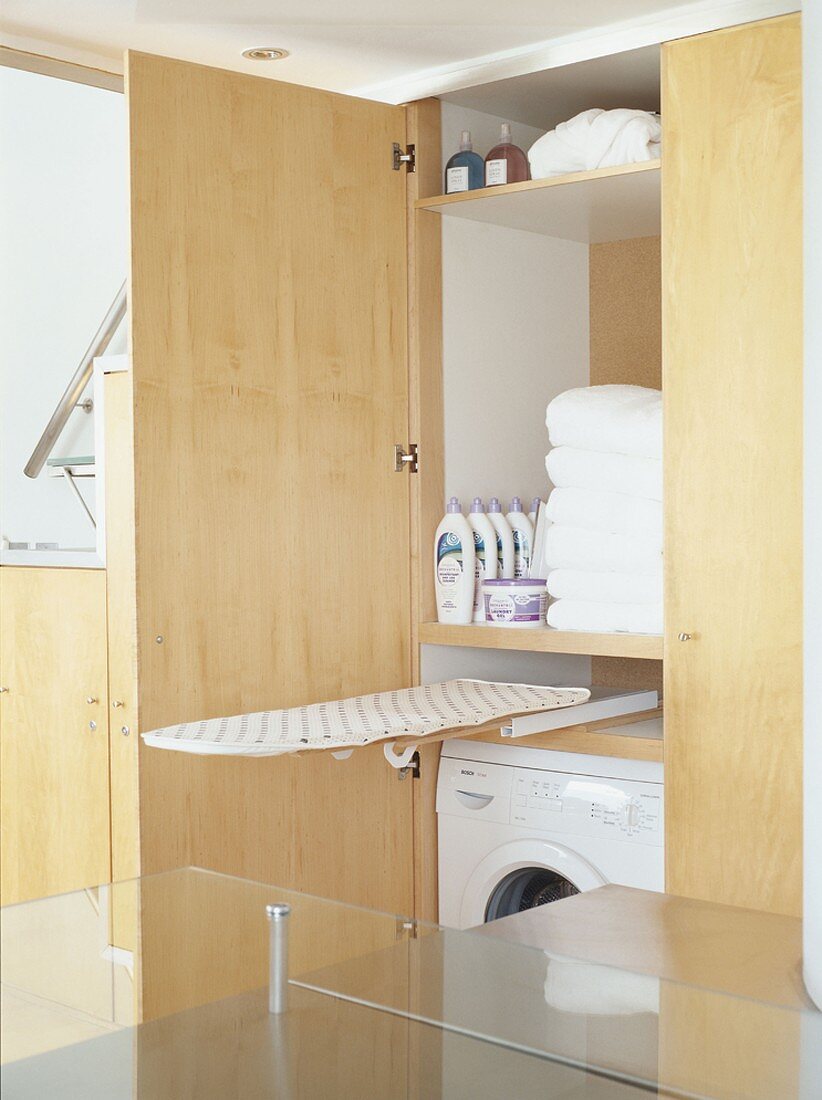 Washing machine, bath towels & ironing board in a cupboard