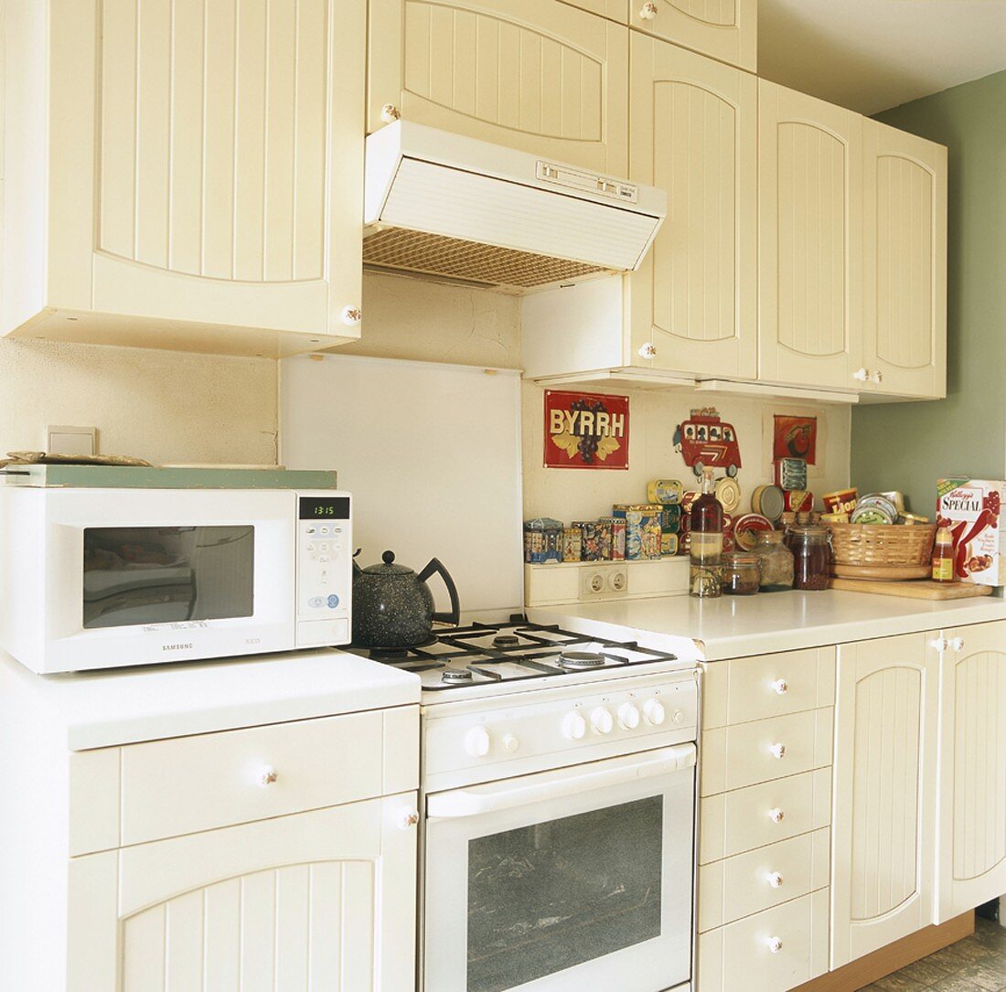 Eine weiße Landhausküche mit Gasherd und alten Geräten