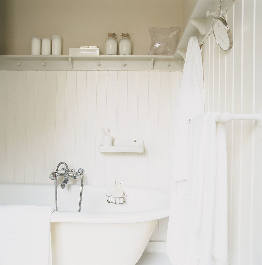 Ein Badezimmer im Landhausstil mit weißen Handtüchern und Bademantel neben Badewanne