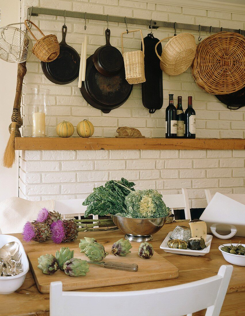 Küchenstilleben mit frischem Gemüse, hängenden Körben und Pfannen