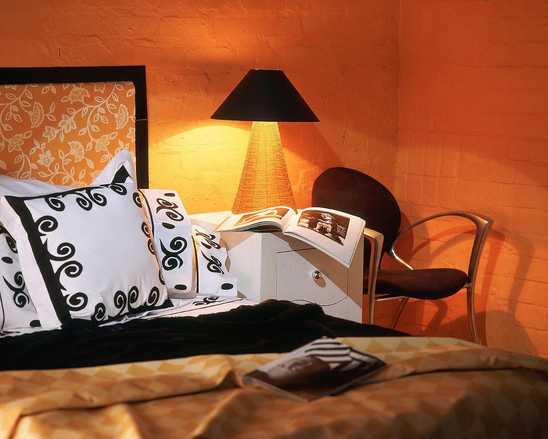 Warmes Licht einer brennenden Nachttischlampe in orangefarbener Schlafzimmerecke