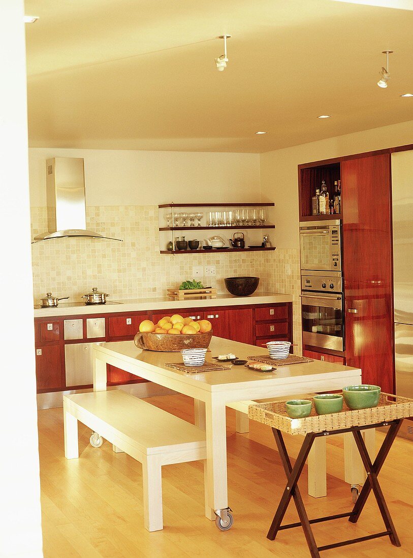 Weisser Esstisch mit Rollen und den dazu passenden Sitzbänken in einer modernen Küche