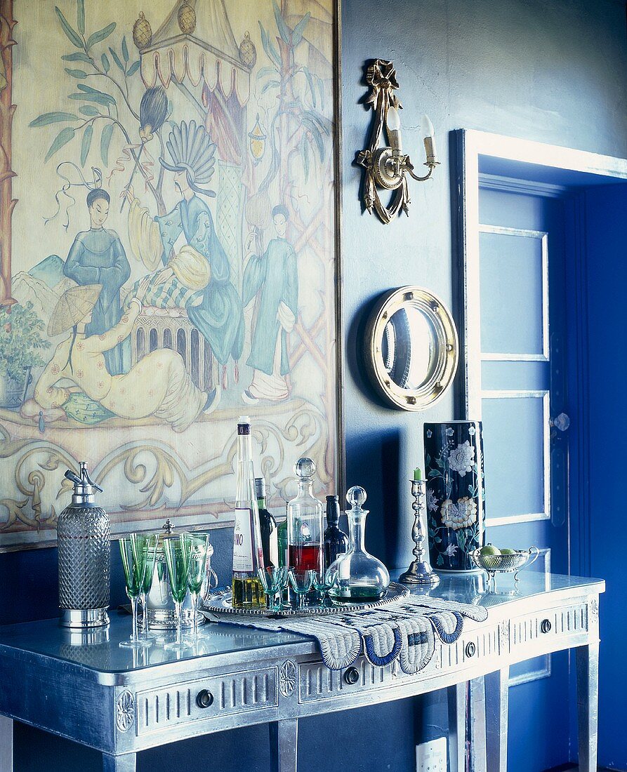 Silver console table in blue room with large Chinese scene on wall
