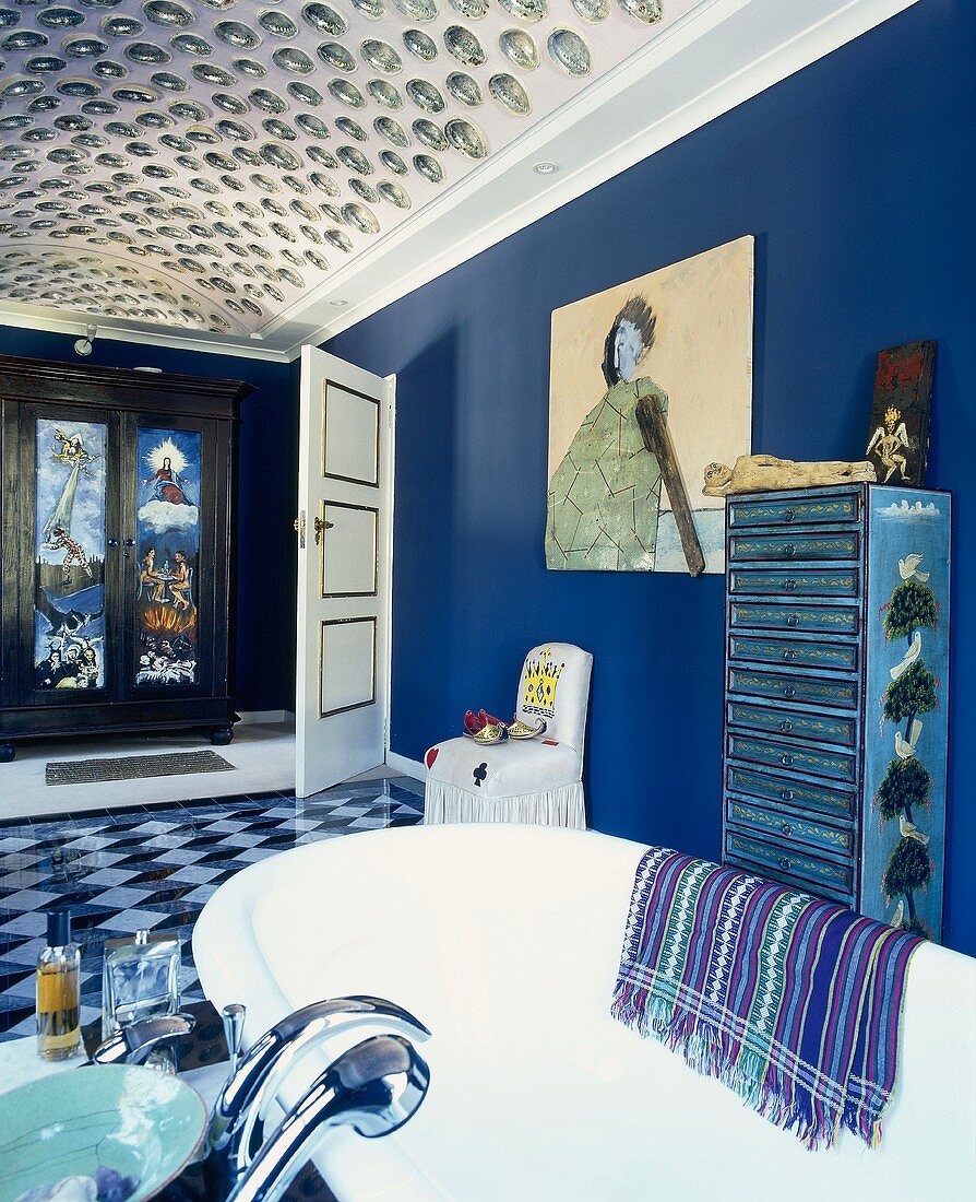 Blue bathroom with vaulted ceiling, painted cabinet, modern painting on wall, objets d'art and free-standing bathtub