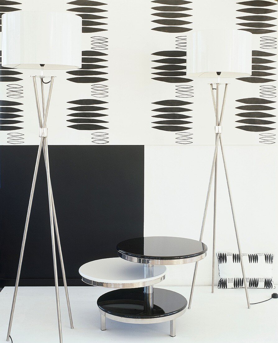 Schwarz-weiss Variationen mit Etagen-Tischchen, zwei Designer-Stehlampen und gemusterter Wandtapete