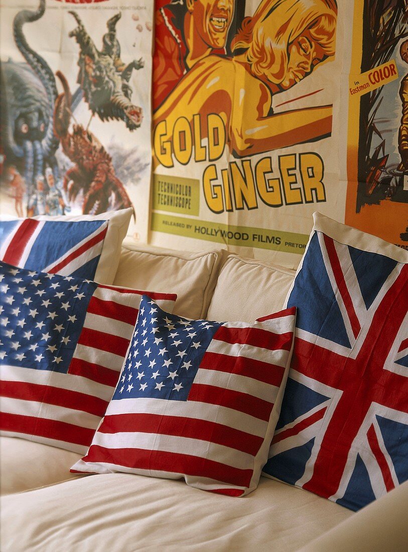 Kissen mit britischer und amerikanischer Flaggen auf weiße Couch vor alten Poster an der Wand