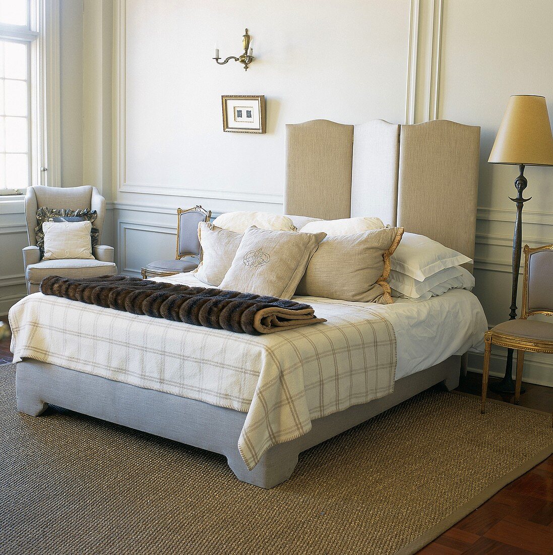 Französisches Bett mit diversen Kissen und Felldecke vor Wandvertäfelung