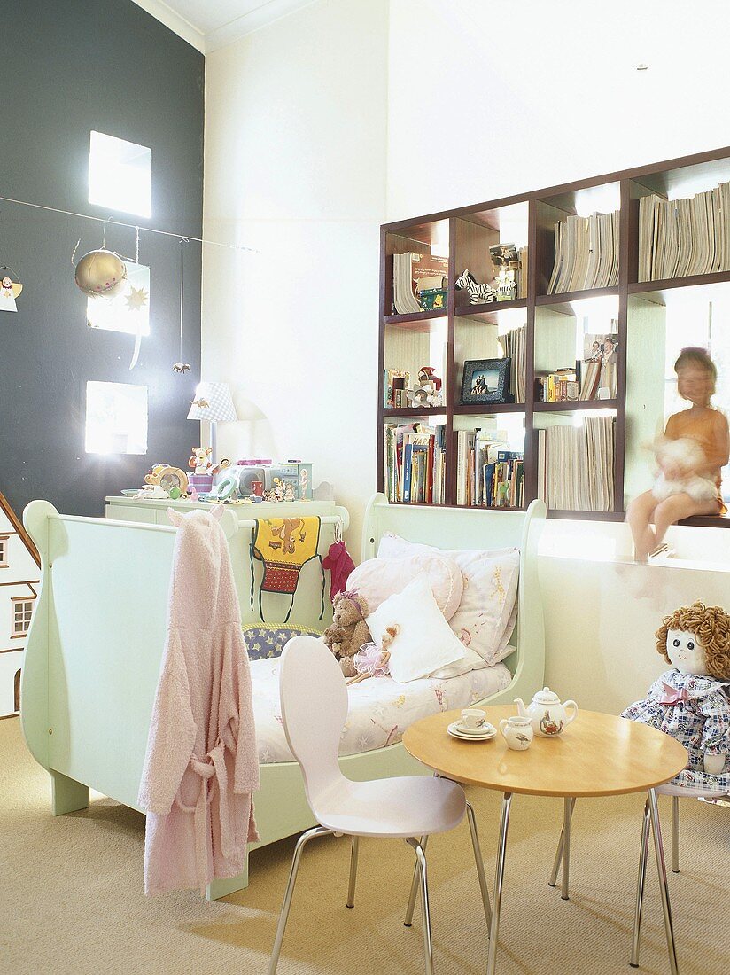 Ein Kinderzimmer mit kleinem Kinderbettchen unter Bücherregal