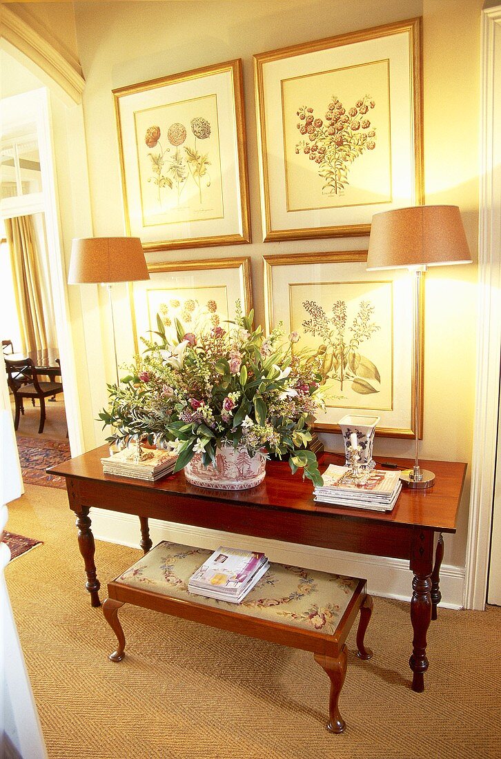 Holztisch und gepolsterte Sitznak vor Blumenbilder an der Wand