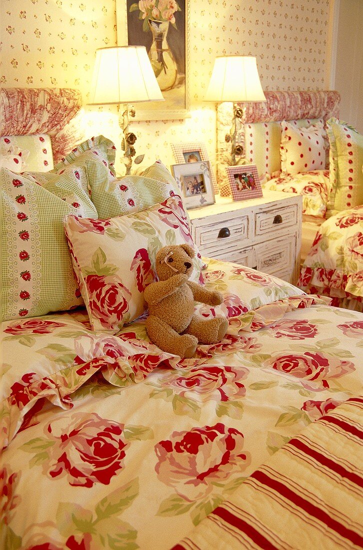 Teddybär auf Einzelbett mit geblümter Bettdecke