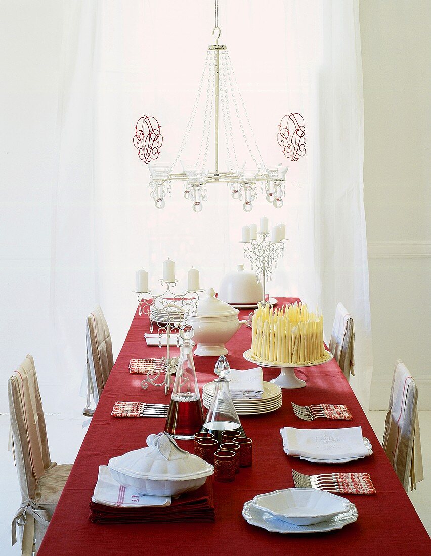 Festlich gedeckter Esstisch mit roter Tischdecke unter Lüster