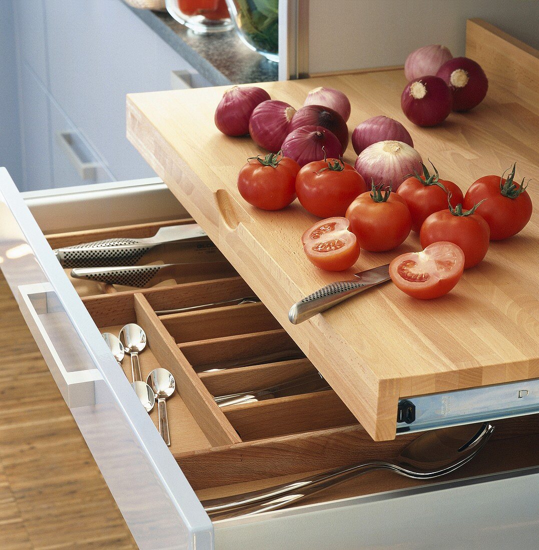 Küchenarbeitsplatte aus Holz mit Tomaten und Zwiebeln, darunter eine Besteckschublade