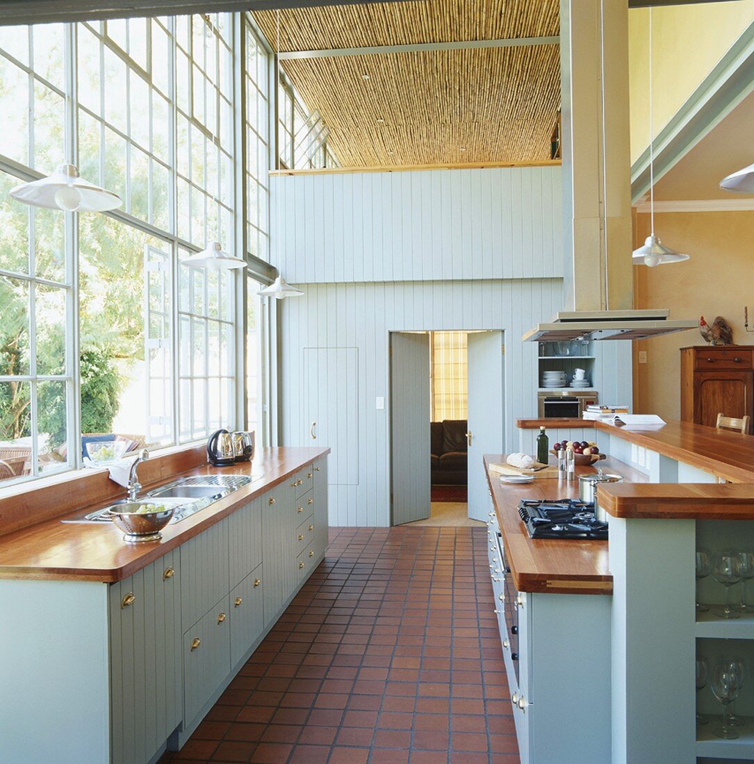 Elegante Vintageküche in Hellblau in einem Loft mit großer Industriefensterfront