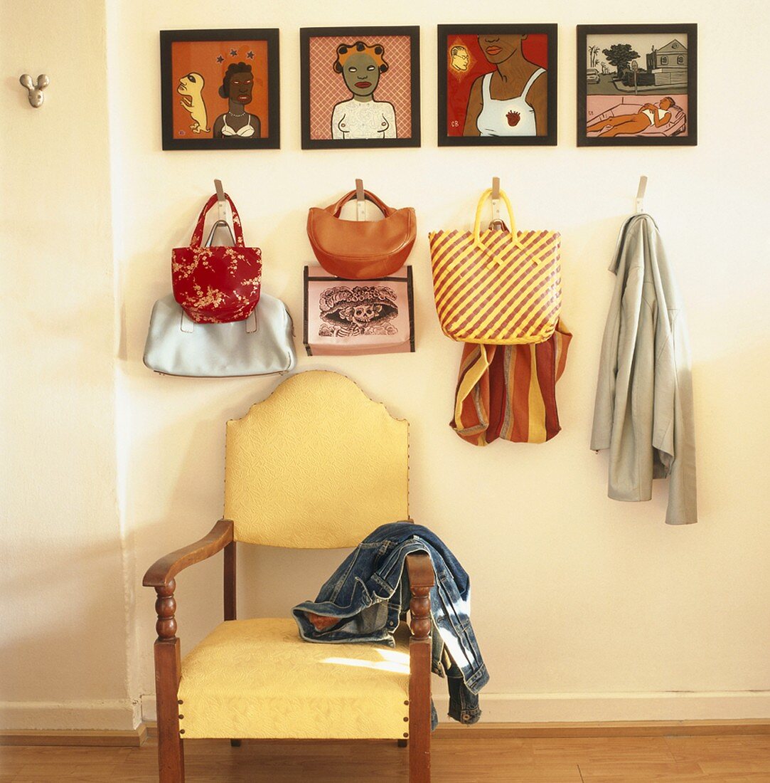 Eine Gemäldeserie und verschiedene Taschen über einem antiken Stuhl