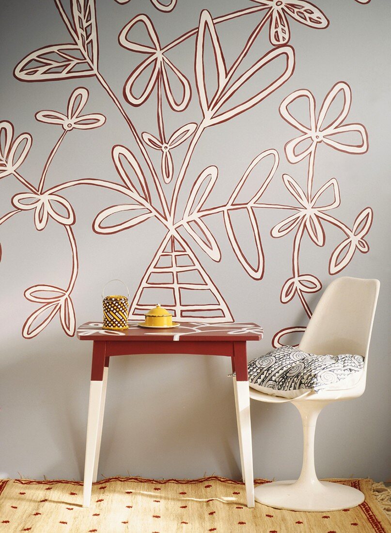 Ein 50er Jahre Stuhl und ein kleiner Tisch vor moderner, floraler Wandmalerei