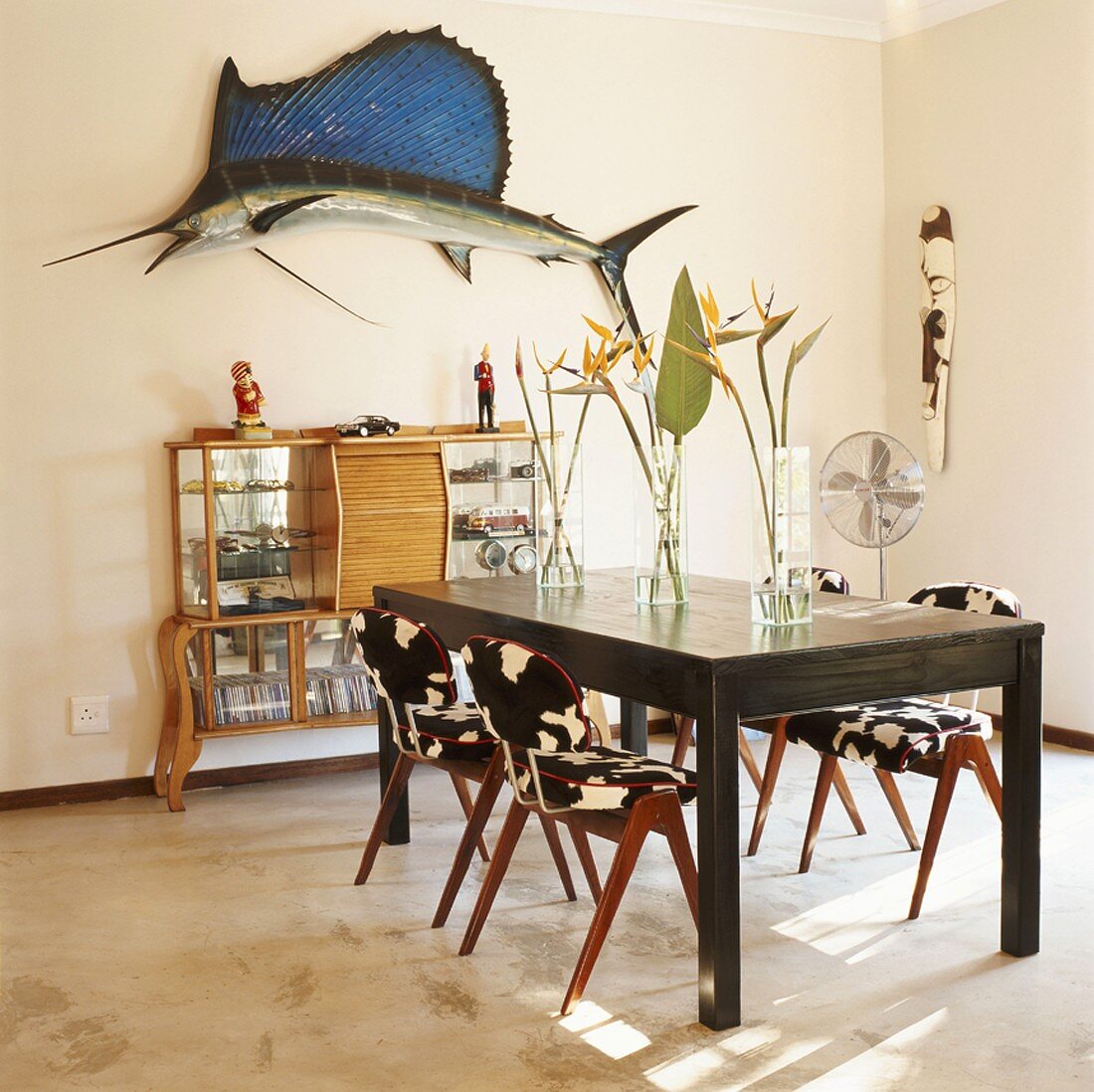 Wohnraum mit Tisch, Stühlen, Wandschränkchen & Wanddekoration
