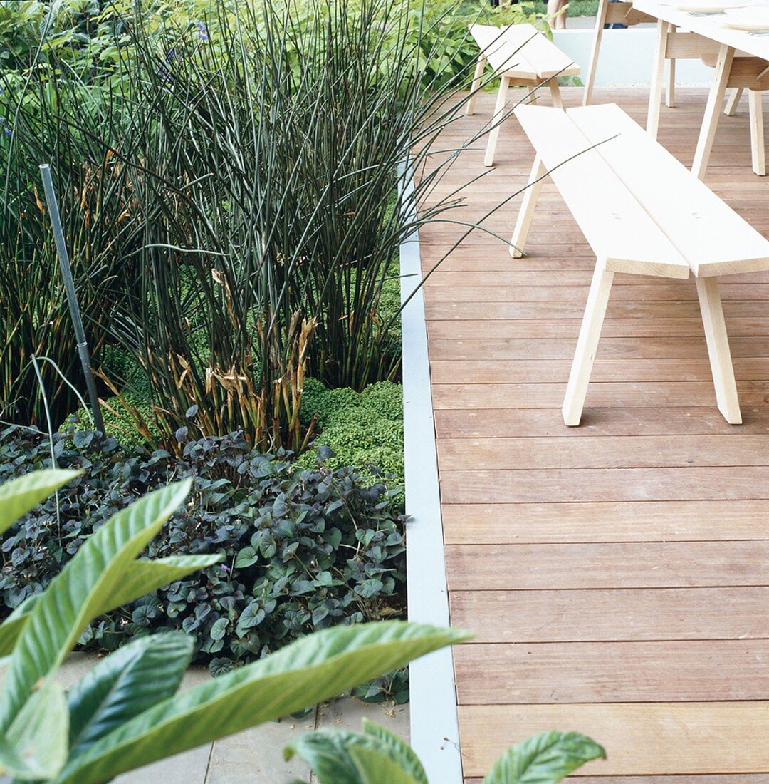 Terrasse mit Holztisch & Holzbänken in Gartenanlage
