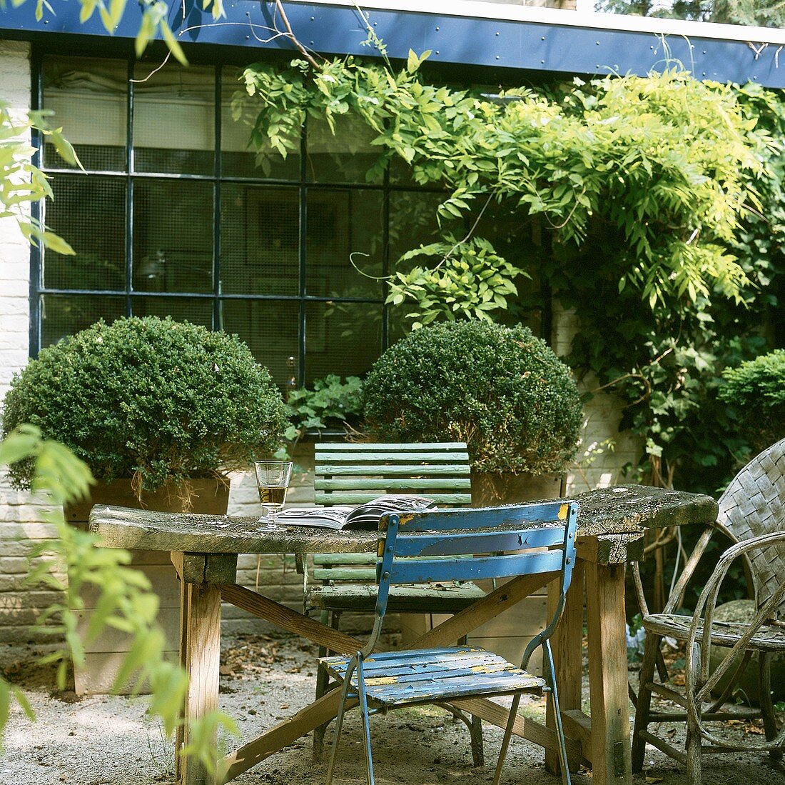Gartentisch mit Klappstühlen und offenes Buch vor Backsteinhaus