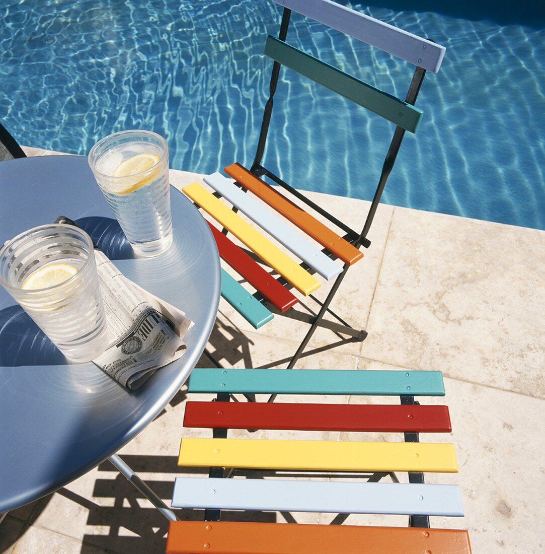 Two glasses on water on table next to pool