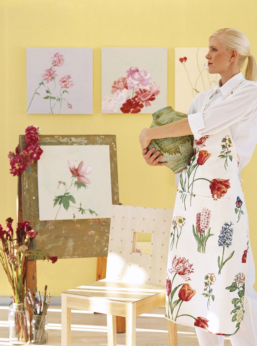 Woman holding vase in front of floral artworks