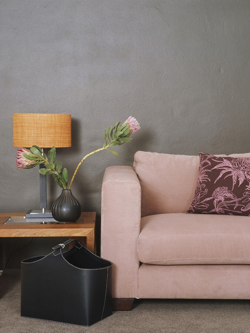 Couch und Tischlampe vor grauer Wand