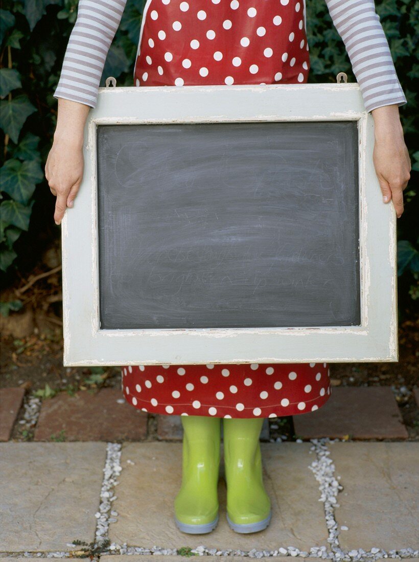 A girl wearing wellie boots holding a chalkboard