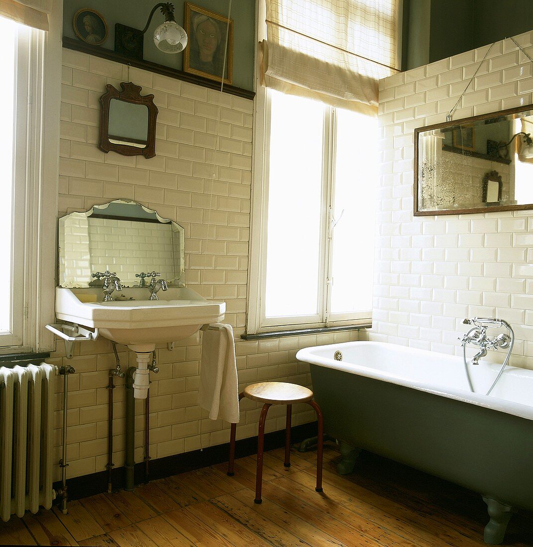 Traditionelles Badezimmer mit antikem Badezimmerspiegel und Waschbecken und einer freistehenden Badewanne