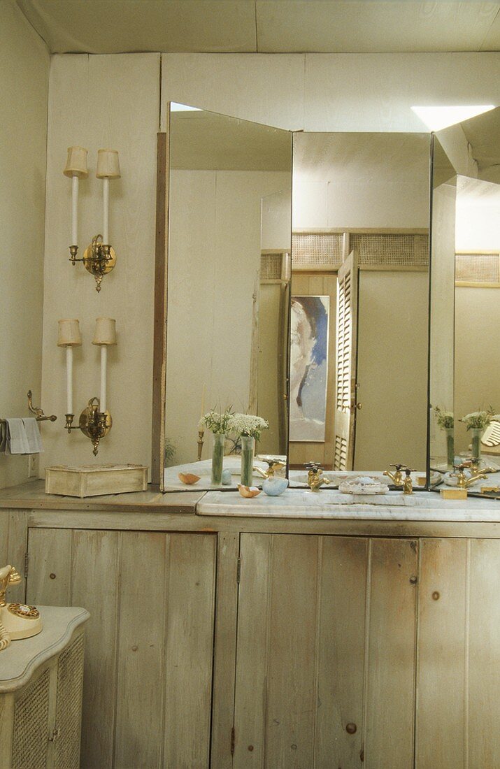 Einfaches Badezimmer mit Holzschränken, einem dreiteiligen Spiegel und einem Steinwaschbecken