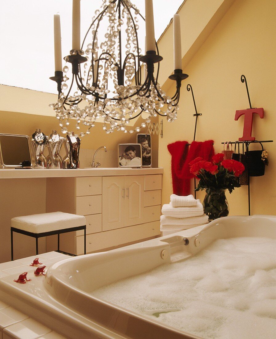 Attic bathroom with large skylight, chandelier and freshly drawn bubble bath