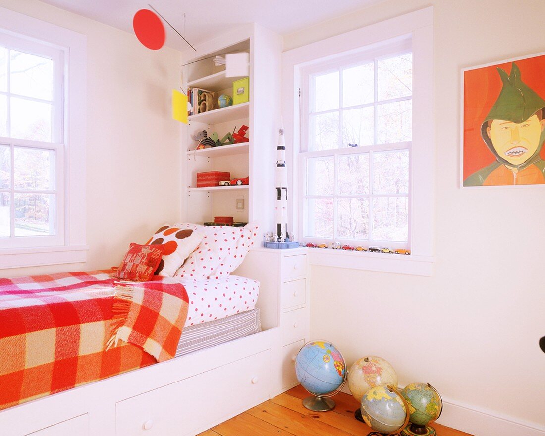 Fröhliches Kinderzimmer mit eingebautem Bettkasten, mit Wandregal und mit leuchtend orangen Farbelementen