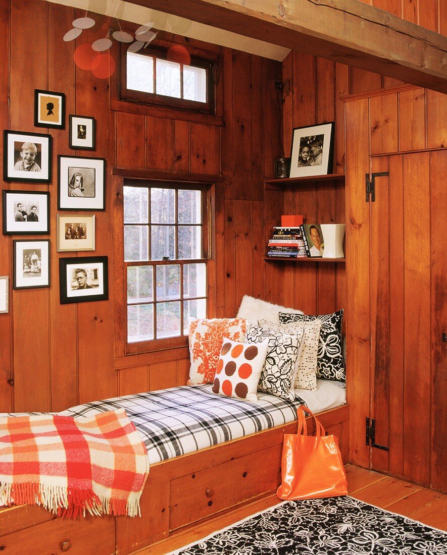 Bequeme Schlafkoje unter dem Schiebefenster in einem einfachen Holzhaus