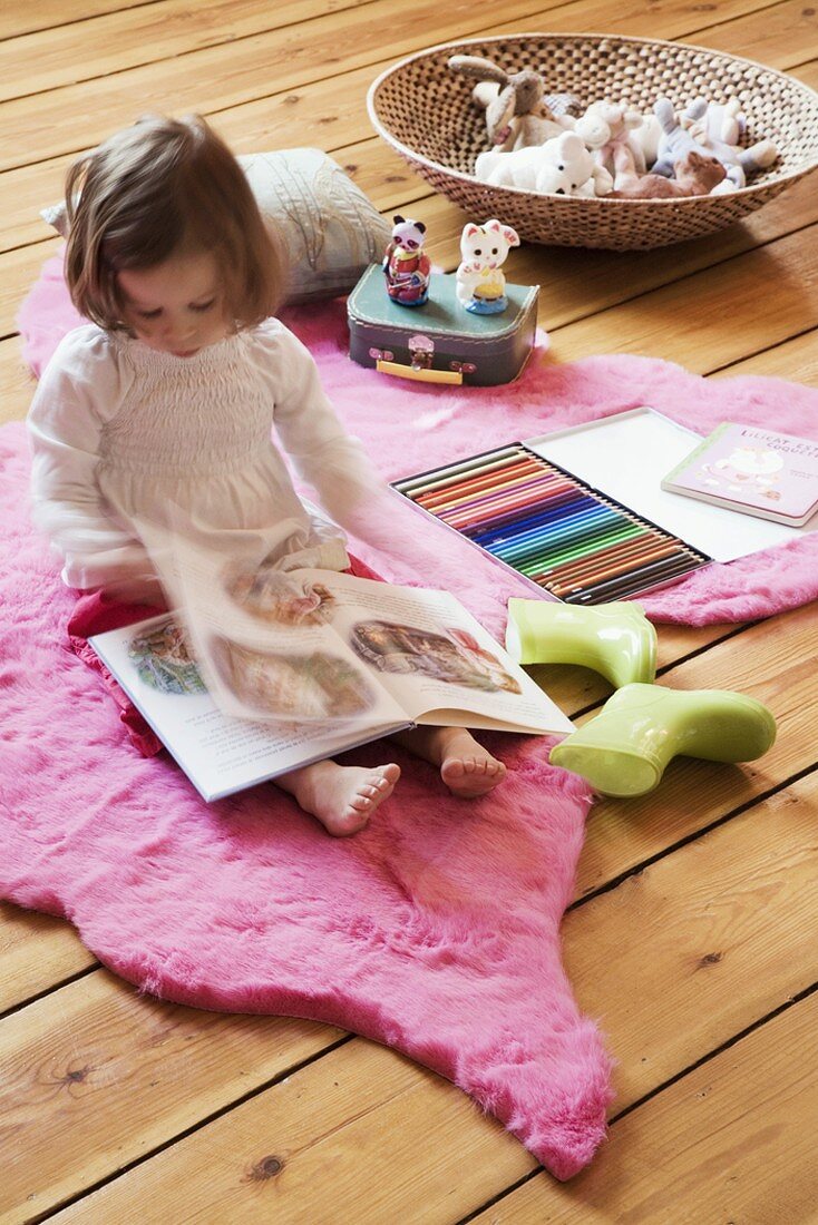 Mädchen liest auf rosarotem Teppich