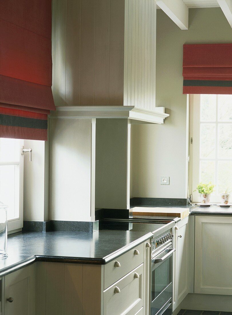 Küchenecke mit roten Raffrollos und Sprossenfenstern