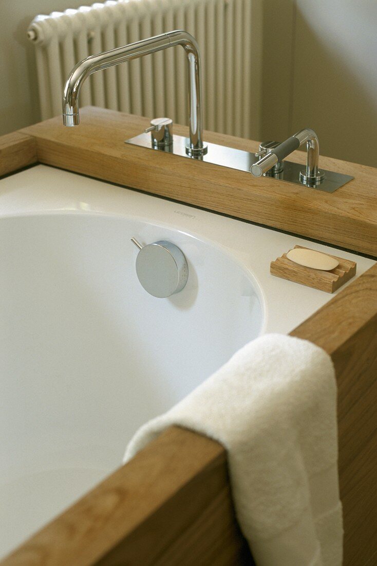 Badewanne mit Holzverkleidung und moderner Armatur