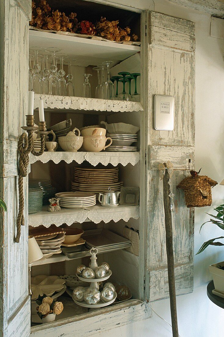 An open wooden cupboard containing crockery
