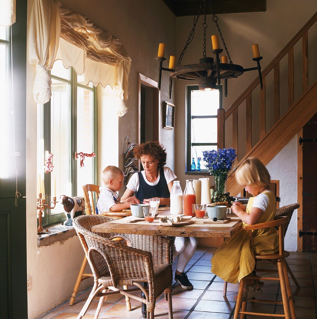 A mother and two children having breakfast in a country house living room