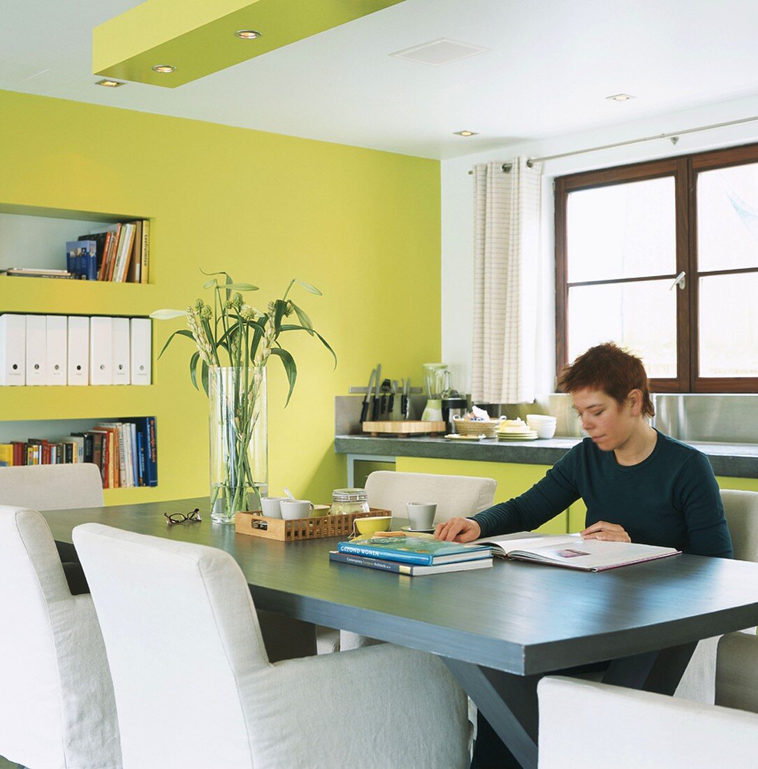 Woman reading at dining table in kitchen