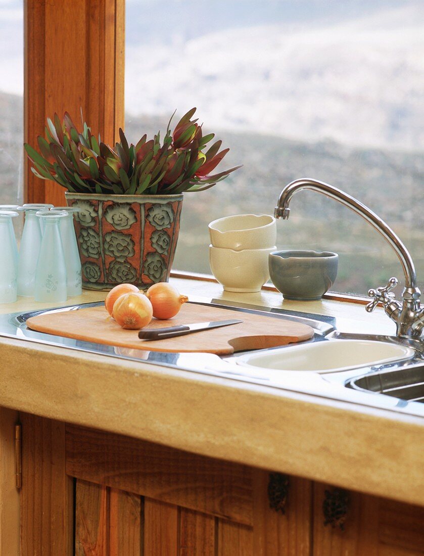 Küchenutensilien auf Spüle vor Fenster in einer Küche