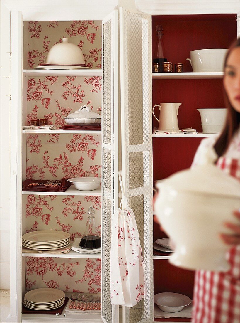 Woman holding soup tureen in front of dresser