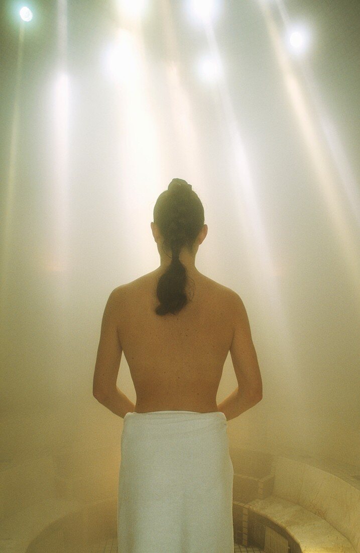 Woman wrapped in towel in steam room
